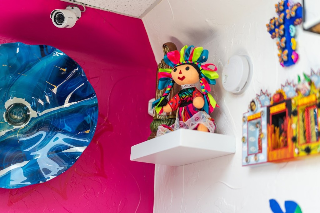 Muñeca de trapo, cruz y piezas de arte popular en esquina del local