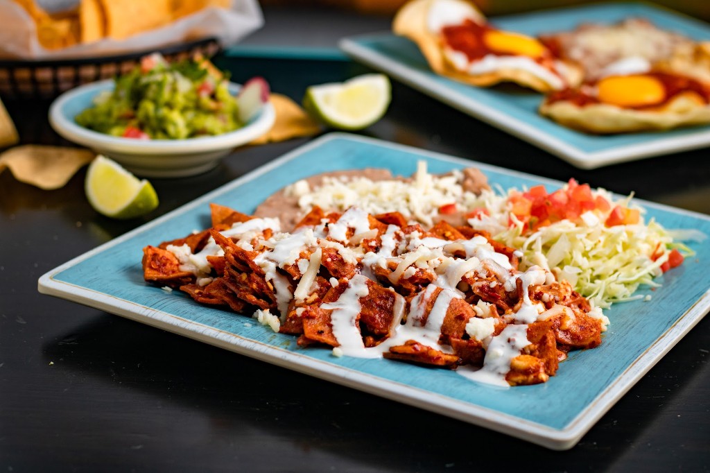 Chilaquiles rojos con crema y queso, frijoles refritos y repollo